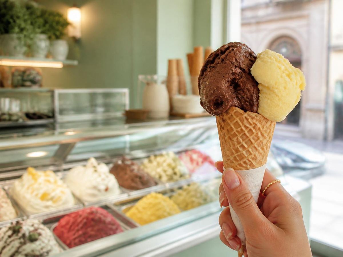 Un cono gelato al cioccolato e limone davanti al banco di una gelateria